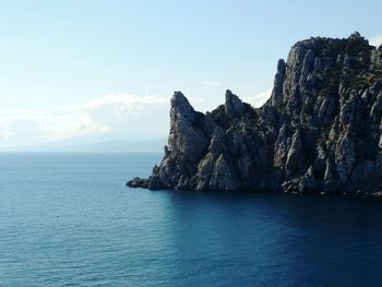 Scenic view of sea and cliff against sky