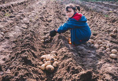 Side view portrait of girl harvesting organic potatoes at farm