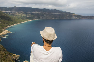 Rear view of man on lake against mountain range