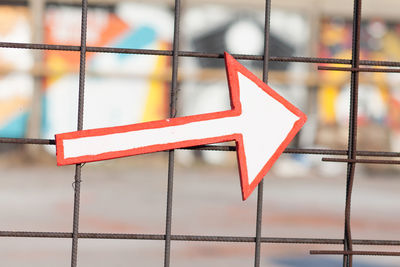 Close-up of arrow symbol on fence