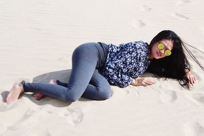 Woman lying down on sand at beach
