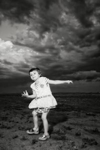 Portrait of girl playing on field against cloudy sky at dusk