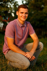 Happy young man. portrait of smiling young brunette man in purple polo shirt seating outdoor 