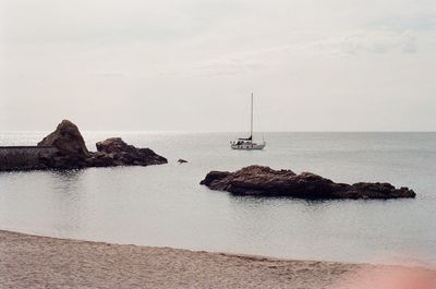 Sailboat on sea shore against sky