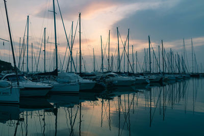 Sailboats moored in marina at sunset