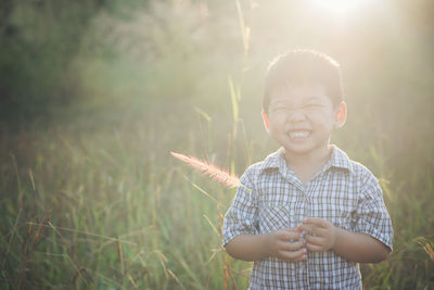 Boy standing on grassy field during sunny day