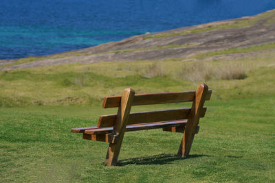 Empty bench on shore by sea