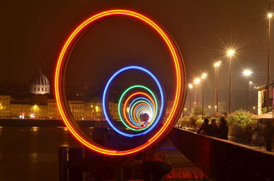 People looking at light painting by river at night