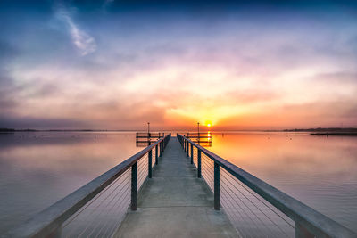 Pier over sea against sky during sunset