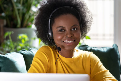 Portrait of smiling woman wearing headphones sitting at home