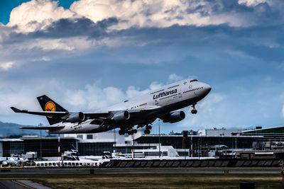 Airplane flying over airport runway against sky