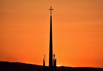 Low angle view of silhouette tower against orange sky