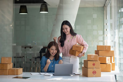 Portrait of smiling young woman using digital tablet while standing in office