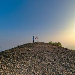 Men standing on rock against clear sky