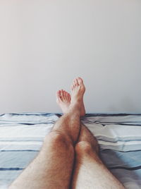 Low section of man lying on bed at home