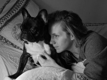 High angle view of young woman with french bulldog relaxing on bed at home