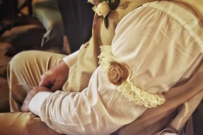Midsection of groom with corsage on hand