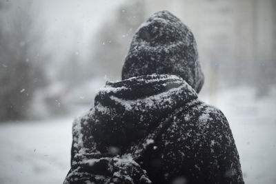 Man outside in snowfall. black clothes in snow. guy is standing in middle of town. blizzard in city. 