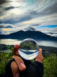 Midsection of person holding sunglasses against sky