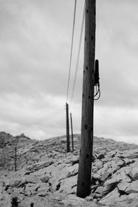 Pole on wooden post on land against sky