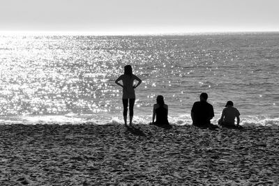 Silhouette people at beach against clear sky