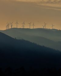 Windmills on mountains against sky during sunset