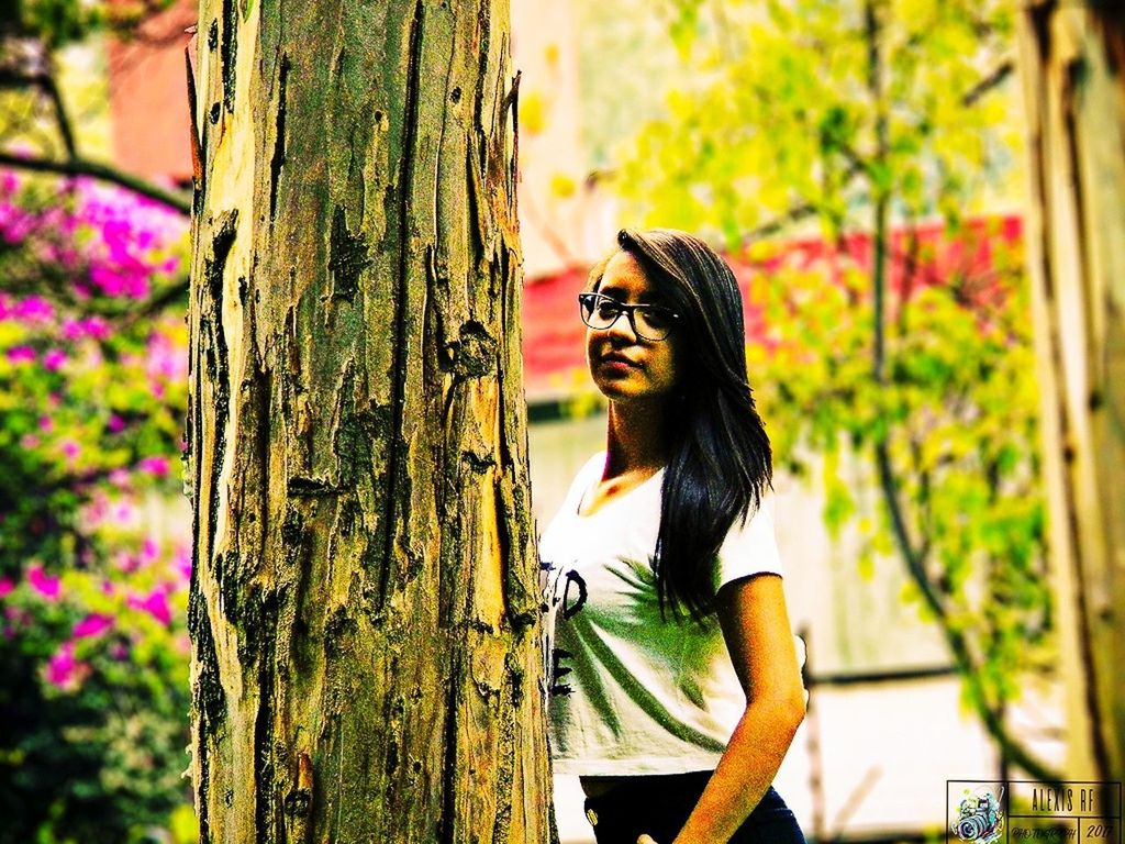 PORTRAIT OF WOMAN BY TREE TRUNK