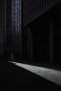 Rear view of man walking by building on street in city