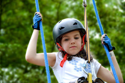 Adventure climbing high wire park - people on course in mountain helmet and safety equipment.