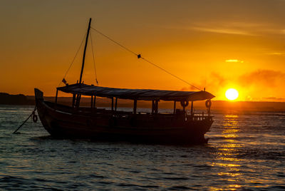 Silhouette fishing boat in sea against sky during sunset