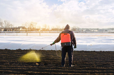 The farmer treats the field from weeds and grass for growing potatoes. use chemicals in agriculture