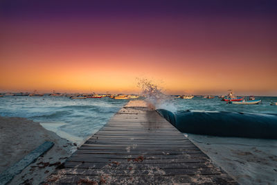 Pier over sea against clear sky during sunset