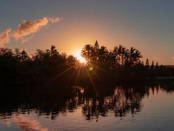 Silhouette trees by lake against sky during sunset