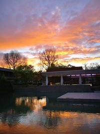Scenic view of lake by building against sky during sunset