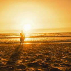 Man on beach against sky during sunset