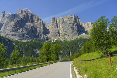 Road amidst trees and mountains against sky