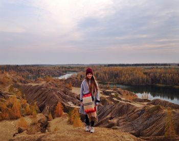 Portrait of young woman standing on landscape against sky