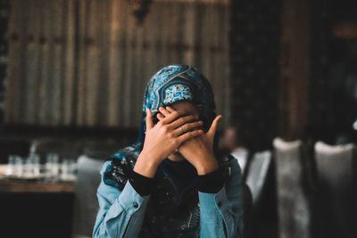 Woman wearing hijab covering face at restaurant