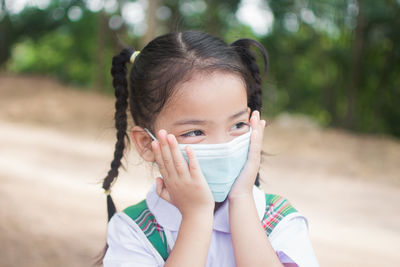 Cute girl wearing mask looking away outdoors