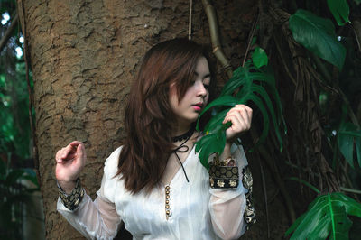 Young woman standing against plants