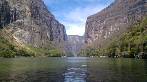 Scenic view of river by mountains against sky