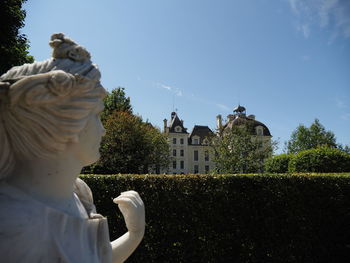 Statue by building against sky