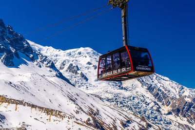 Ski lift over snowcapped mountains against sky