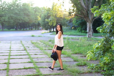 Full length portrait of young woman standing on footpath