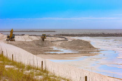 Heavy equipment replenish the shoreline with dredged sand
