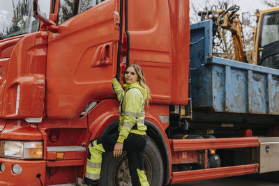 Portrait of female construction worker opening truck door