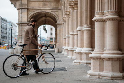 Young man holding smartphone and walking with bicycle. eco friendly transport.