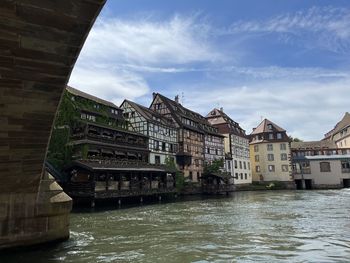 Buildings by river against sky