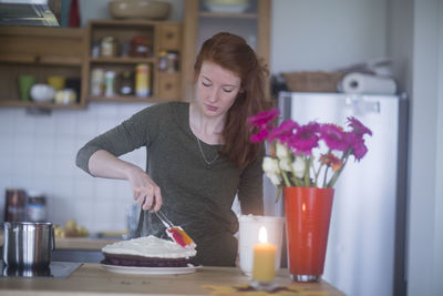 Young woman making birthday cake at home