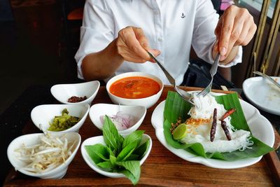 Midsection of man with food on table sitting in restaurant